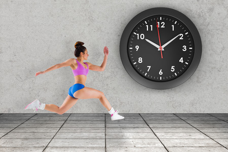 Composite image of fit brunette running against grey roomの写真素材