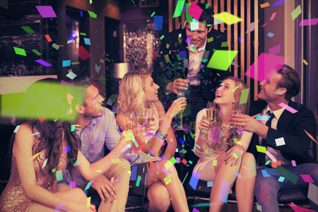 Stylish friends having a drink together against flying coloursの写真素材