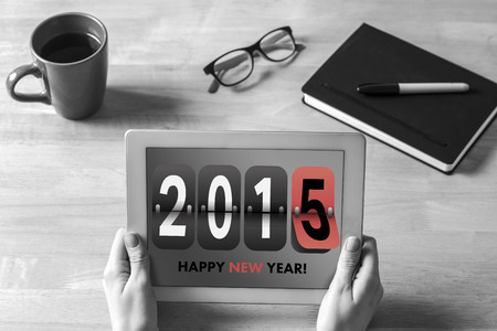 Businesswoman holding tablet at desk against happy new year 2015の写真素材