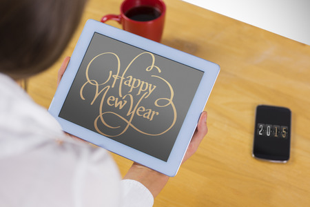Businesswoman using tablet at desk against happy new yearの写真素材