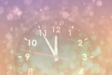 Clock counting down to midnight against pink abstract light spot designの写真素材