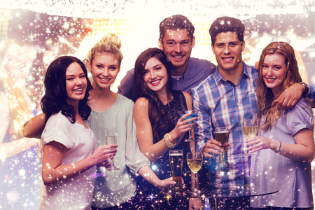 Friends with drinks against gold and red lightsの写真素材