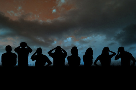 Silhouettes of football supporters against blue sky over grassの写真素材