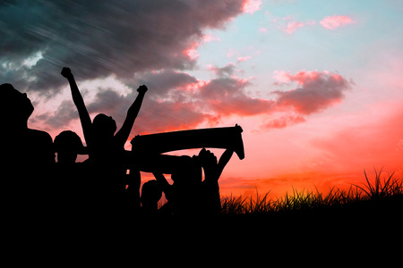 Silhouettes of football supporters against red sky over grassの写真素材