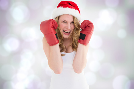 Blonde woman wearing boxing gloves smiling at camera against purple abstract light spot designの写真素材