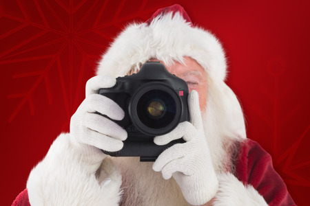 Santa is taking a picture against red backgroundの写真素材
