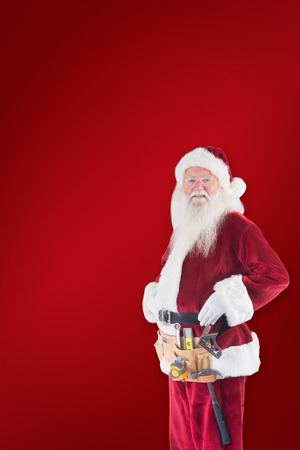 Father Christmas is wearing a tool belt against red backgroundの写真素材
