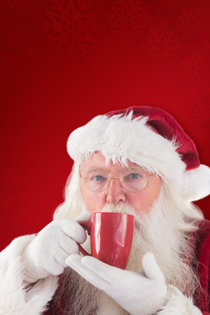 Santa drinks from a red cup against red backgroundの写真素材