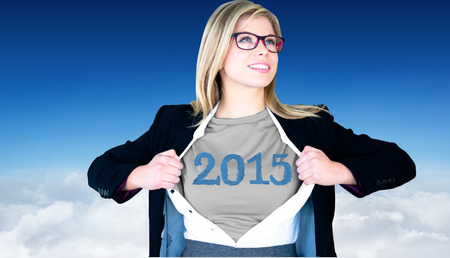 Businesswoman opening shirt in superhero style against blue sky over cloudsの写真素材