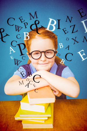 Cute pupil at desk against blue backgroundの写真素材