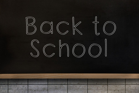 Back to school message against blackboard on wall