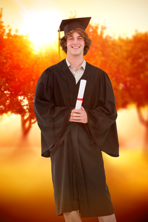 Smiling student in graduate robe against sunrise over treesの写真素材