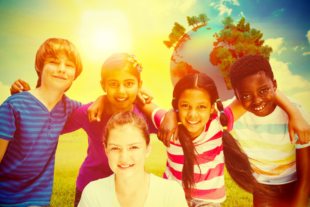 Happy children forming huddle at park against blue sky over green fieldの写真素材
