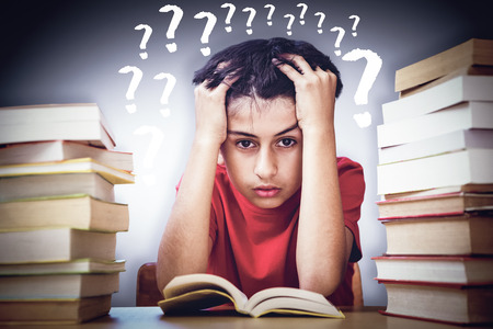 Tensed boy sitting with stack of books against grey vignette