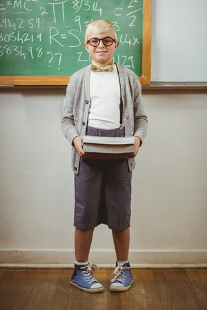 Portrait of smiling pupil dressed up as teacher holding books in a classroomの写真素材