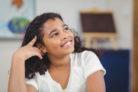 Cute pupil daydreaming in a classroom in schoolの写真素材