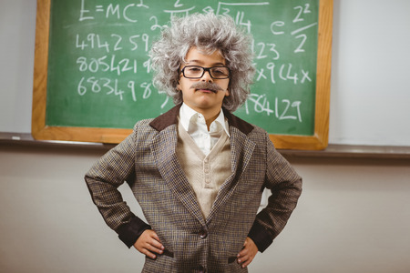 Portrait of little Einstein posing in front of chalkboard in a classroomの写真素材