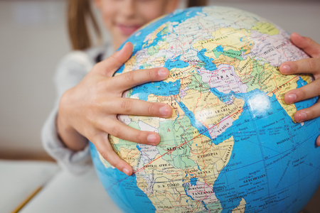 Pupil holding globe in a classroom in schoolの写真素材