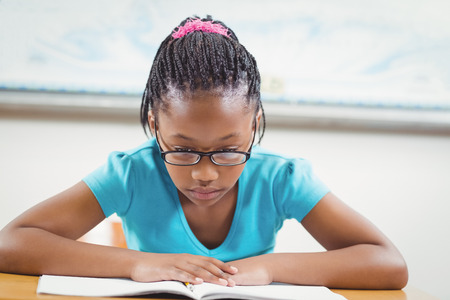 Focused pupil reading book in a classroom in schoolの写真素材