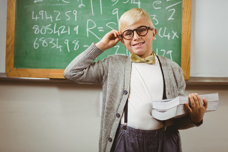 Portrait of smiling pupil dressed up as teacher holding books in a classroomの写真素材
