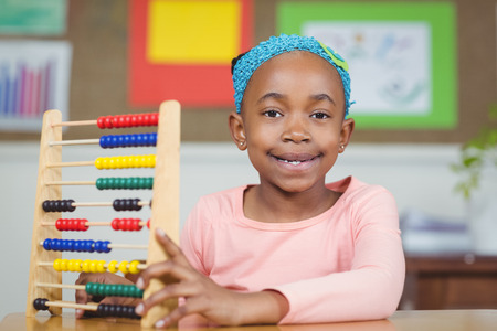 Portrait of smiling pupil calculating with abacus in a classroom in school