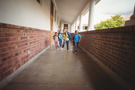 Happy pupils walking at corridor in schoolの写真素材