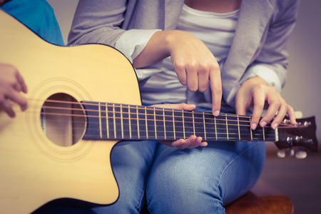 Teacher giving guitar lessons to pupil in a classroom
