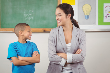 Pretty teacher and cute pupil in front of chalkboard in a classroomの写真素材