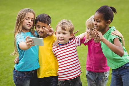 Smiling classmates posing and taking selfies on campusの写真素材