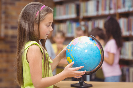 Pupil in library looking at globe at the elementary schoolの写真素材