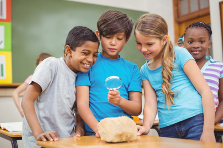 Pupils looking at rock with magnifying glass at the elementary school
