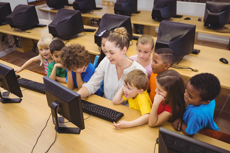 Teacher showing students how to use a computer at the elementary school