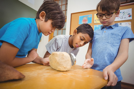Pupils looking at rock with magnifying glass at the elementary schoolの写真素材