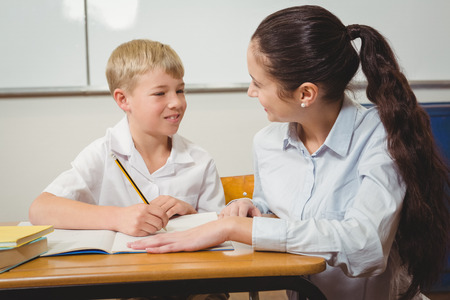 Teacher helping a student in class at the elementary schoolの写真素材