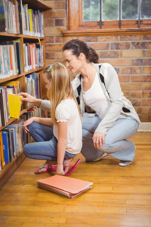 Teacher helping a student pick a book at the elementary schoolの写真素材