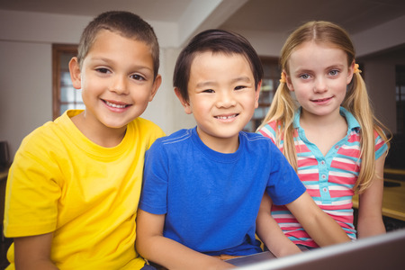 Cute pupils in computer class using laptop at the elementary school