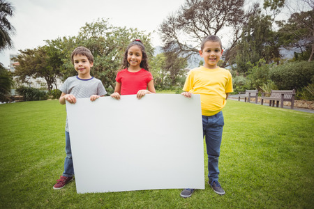 Cute pupils showing large poster on elementary school campusの写真素材