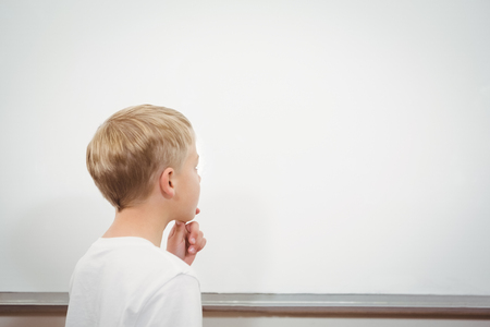 Puzzled student looking at whiteboard at the elementary schoolの写真素材