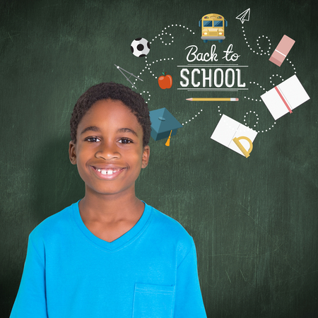Cute boy smiling at camera against green chalkboard