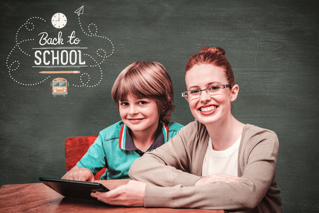 Happy pupil and teacher against green chalkboard