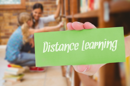 The word distance learning and hand showing card against teacher and little girl selecting book in...