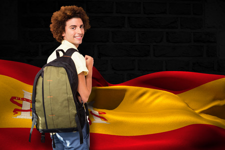 Casual young man in office corridor against digitally generated spain flag rippling