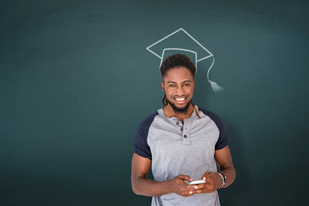 Young casual man text messaging against teal, blueの写真素材