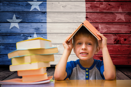 Cute boy with book on head against composite image of usa national flagの写真素材