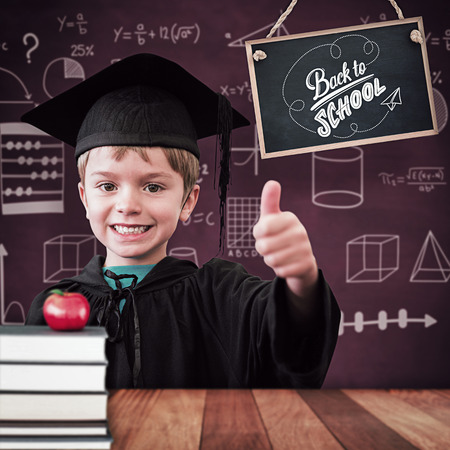 Cute pupil in graduation robe against wooden surface with planksの写真素材