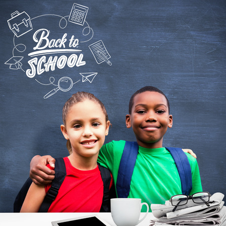 Cute pupils smiling at camera  against blue chalkboardの写真素材