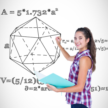 Pretty brunette writing and holding notebook  against geometry problemの写真素材