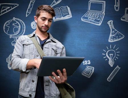 Student using tablet in library  against blue chalkboardの写真素材