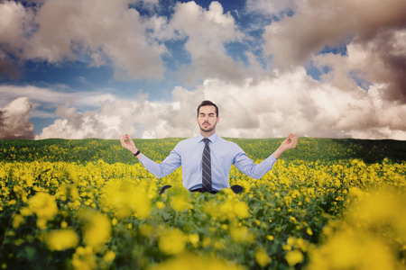 Calm businessman sitting in lotus pose against nature sceneの写真素材