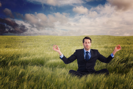 Calm businessman sitting in lotus pose against nature sceneの写真素材
